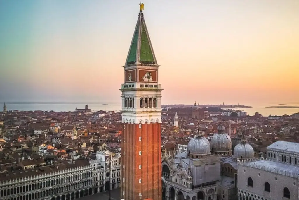 Venice bell tower during sunset with cityscape view.