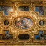 Ornate ceiling with classical paintings and gold details.