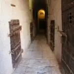 Narrow stone corridor with heavy wooden doors.