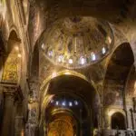 Interior of ornate cathedral with golden mosaics.
