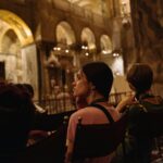 People sitting in an ornate, historic church interior.